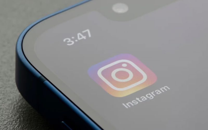 A young woman looking confused at her phone, which shows no new Instagram posts.