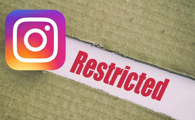 A person holding a phone and successfully viewing the profile and posts of an account that has restricted them on Instagram.